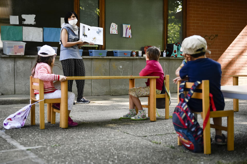 IVREA, TURIN, ITALY - 2020/05/26: A teacher reads a book to kindergarten children in a school garden. Municipality of Ivrea opens the gardens of two kindergarten schools as part of a pilot test to see how schools can reopen after COVID-19 coronavirus lockdown. (Photo by Nicolò Campo/LightRocket via Getty Images)