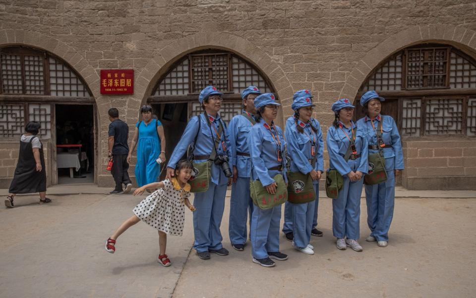 Tourists wearing Red Army uniforms pose for photos in front of the former residence of Mao Zedong at the Yangjialing Revolutionary Site in Yan'an. - ROMAN PILIPEY/EPA-EFE/Shutterstock 