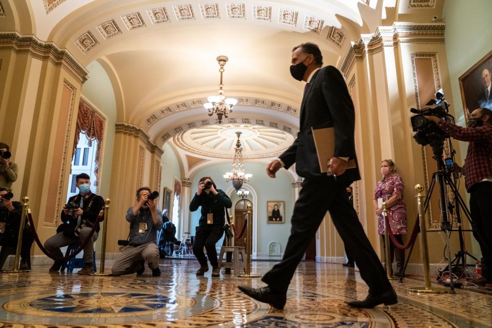 A senator walks in front of a few photographers in the Capitol