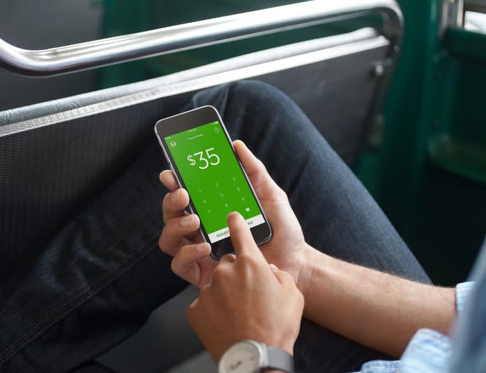 A person holding a phone displaying Cash App.