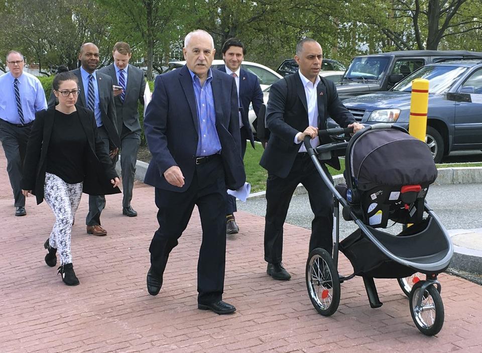 In this May 8, 2019 photo, Providence Mayor Jorge Elorza, right, pushes his son Omar in a baby carriage as he walks to the Rhode Island Statehouse for a meeting with the governor in Providence, R.I. Walking with Elorza are Emily Crowell, left, his communication director, and Johnston, R.I., Mayor Joseph Polisena, center. Elorza's decision to frequently take his son to work with him has brought praise from some who say he's a role model, but also raised questions about whether he has taken it too far. (Steve Klamkin/WPRO News via AP)