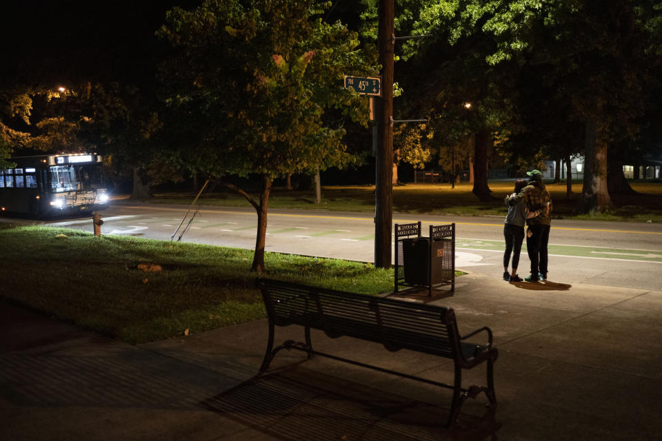 Navada Gwynn, right, embraces his daughter, Victoria, 21, while waiting with her at dawn for the bus to take her to work in Louisville, Ky, Tuesday, Aug. 29, 2023. Krista Gwynn recalls that after their 19-year-old son, Christian, was killed in a drive-by shooting four blocks from home in 2019, Navada blamed himself for not doing more to protect him. Just two years later, Victoria, then also 19, was shot and injured at a park. Now the Gwynns have pulled their youngest child, Navada, out of school, home schooling to keep her safe. (AP Photo/David Goldman)