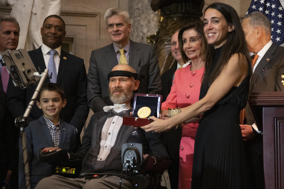 A Congressional Gold Medal is presented to amyotrophic lateral sclerosis (ALS) advocate and former National Football League (NFL) player, Steve Gleason, in Statuary Hall on Capitol Hill, Wednesday, Jan. 15, 2020, in Washington. Holding the medal is his wife Michel Gleason. (AP Photo/Manuel Balce Ceneta)