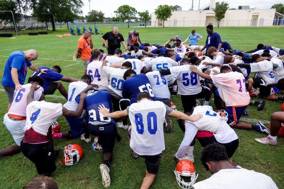 Palm Beach Gardens High School players and coaches say a prayer after an afternoon of practice on July 31, 2015.  (Richard Graulich / The Palm Beach Post)