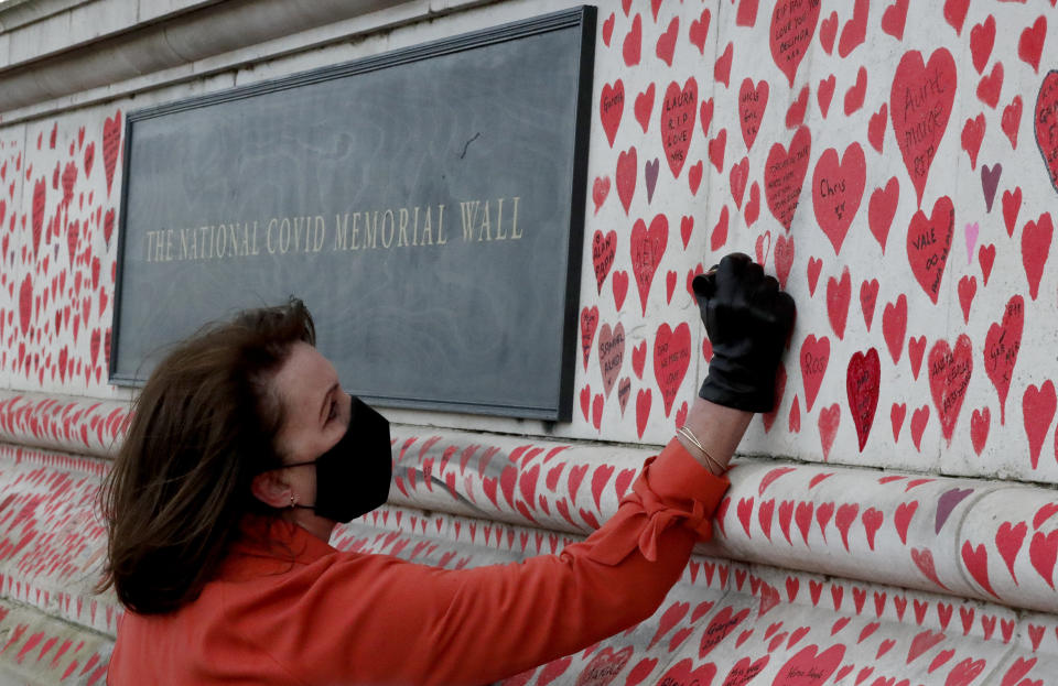 Fran Hall draws the last hearts as families bereaved by Covid-19 mark the completion of the approximately 150,000 hearts being painted onto the National Covid Memorial Wall, on the Thames Embankment opposite the Houses of Parliament in London, Thursday, April 8, 2021. Bereaved families want the wall of painted hearts to remain a site of national commemoration and are asking the Prime Minister to help make the memorial permanent. (AP Photo/Frank Augstein)