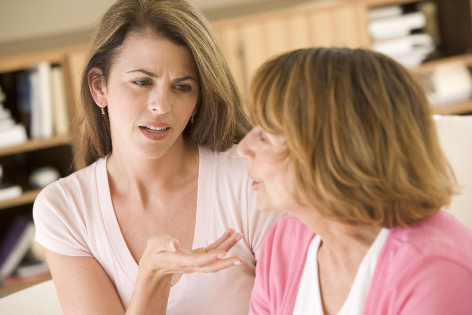 Two women sitting in living room arguing with each other having a discussion