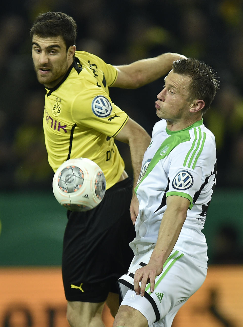 Dortmund's Sokratis, left, and Wolfsburg's Ivica Olic challenge for the ball during the semifinal match of the German soccer cup between Borussia Dortmund and VfL Wolfsburg in Dortmund , Germany, Tuesday, April 15, 2014. (AP Photo/Martin Meissner)