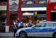 Police stand outside where a 21-year-old Syrian refugee killed a woman with a machete and injured two other people in the city of Reutlingen, Germany July 24, 2016. REUTERS/Vincent Kessler