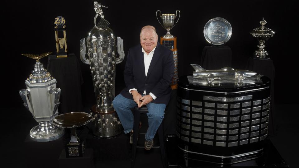 Chip Ganassi sits with some of the trophies his racing teams have won, including the Indy 500, Daytona 500 and 24 Hours of Le Mans.