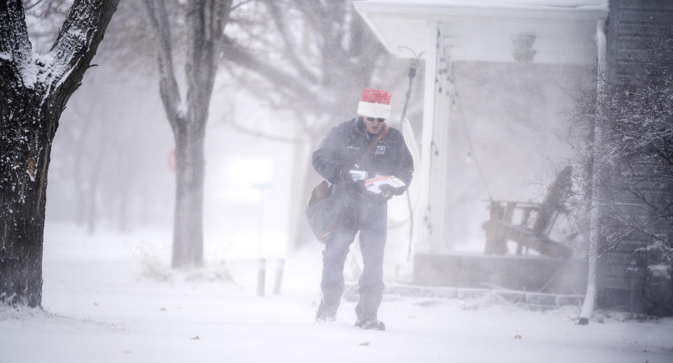 Mail carrier Dennis Niles braves the blowing snow as blizzard like conditions hit Osseo and the Twins Cites on Wednesday, Dec. 23, 2020 in Osseo, Minn. (Jerry Holt/Star Tribune via AP)