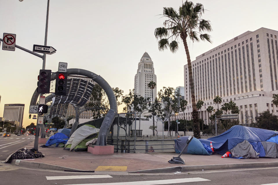 FILE - This March 27, 2020 file photo shows homeless people camping in downtown in Los Angeles.A judge has approved an agreement in which the city and county of Los Angeles will provide housing for almost 7,000 homeless people who live near freeways. Officials said Thursday, June 18, 2020 the city will provide 6,000 new beds within 10 months and another 700 beds over 18 months. Meanwhile the county will spend $300 million over five years to fund services for the people. (AP Photo/Damian Dovarganes, File)