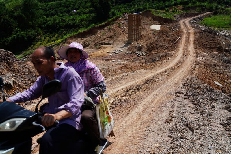 FILE PHOTO: People ride on a vehicle at a dam that collapsed following heavy rainfall at the Shazixi reservoir in Yangshuo