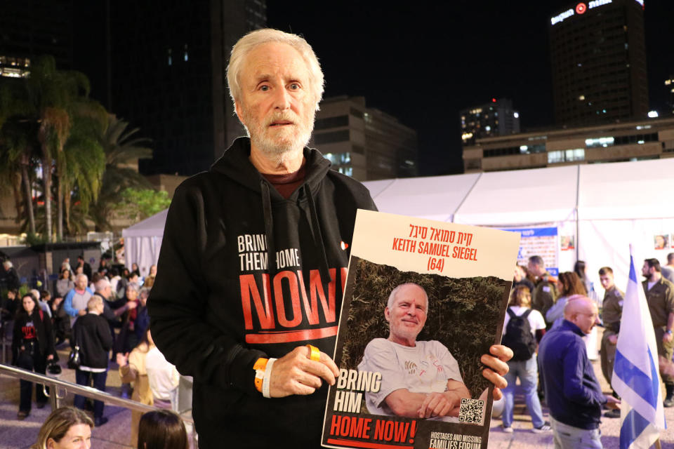 Lee Siegel stands in 'Hostage Square' in Tel Aviv holding up a sign with his brother's photo. (Chantal Da Silva)