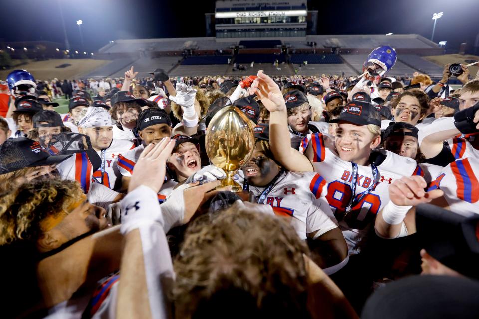 Bixby celebrates with the trophy after beating Jenks 49-21 in the Class 6A-I football championship Friday at UCO's Chad Richison Stadium in Edmond.