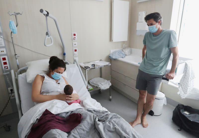 Amandine, who tested positive for the coronavirus disease (COVID-19) just before giving birth, and Francois, wearing a protective face masks, are pictured with their newborn daughter Mahaut at the maternity at CHIREC Delta Hospital in Brussels