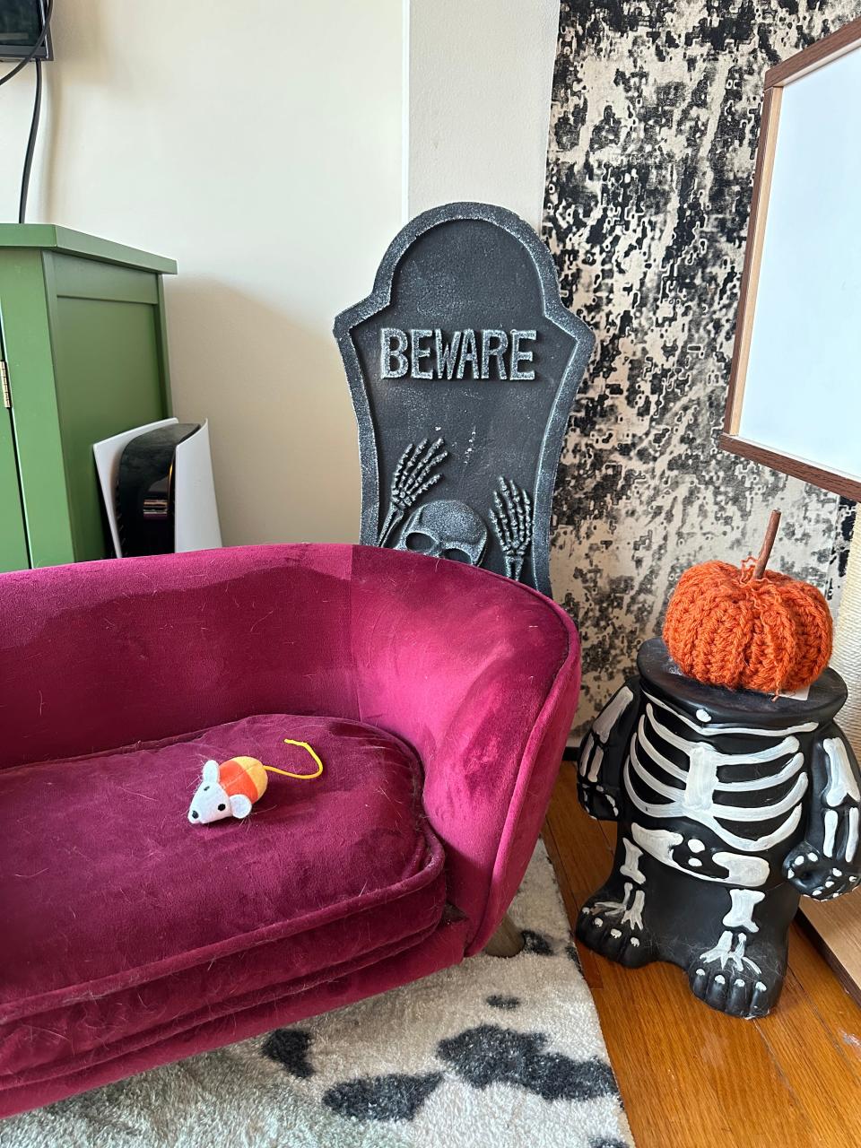 Halloween decorations at the author's apartment, including a skeleton with a pumpkin head and a cardboard gravestone.