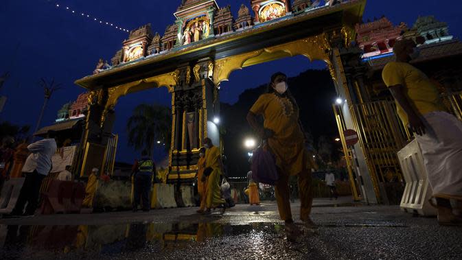 Umat Hindu yang mengenakan masker memasuki pintu masuk kuil Sri Subramaniyar selama festival Thaipusam karena umat mematuhi prosedur operasi standar yang ketat karena pandemi COVID-19 di Gua Batu di pinggiran Kuala Lumpur, Malaysia, Selasa (18/1/2022). (AP Photo/ Vincent Thian)