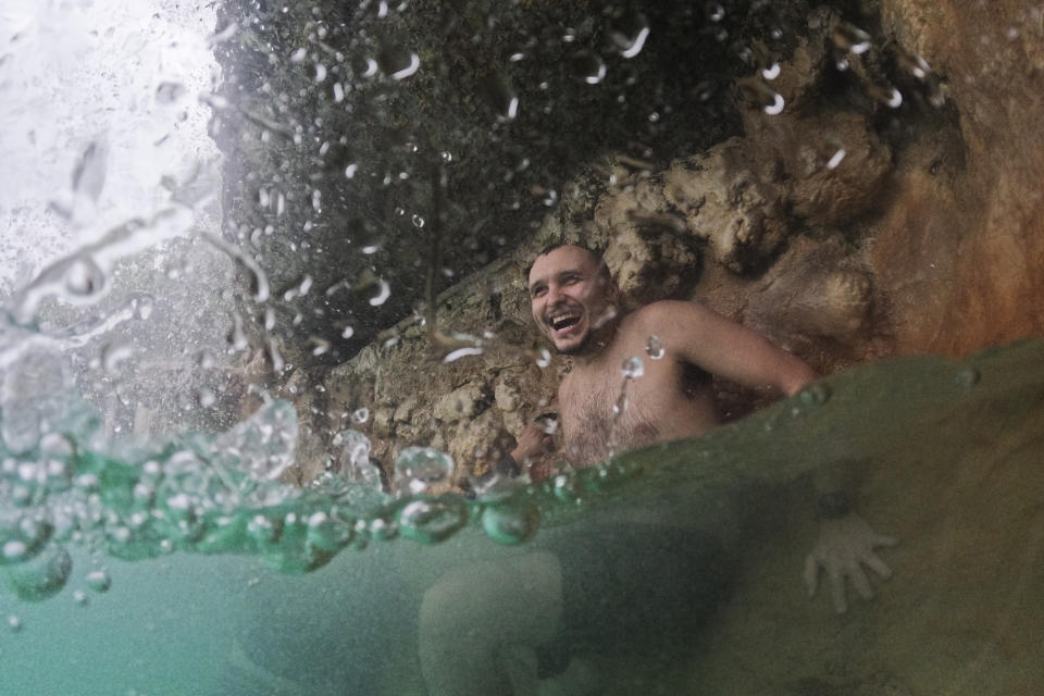 FILE - A young man cools off under a waterfall on a cloudy day with temperatures in the high 80s and intermittent rain storms, during a respite from an ongoing heat wave, at the aquifer-fed Venetian Pool in Coral Gables, Fla., July 27, 2023. Nearly 60% of the U.S. population, are under a heat advisory or flood warning or watch as the high temperatures spread and new areas are told to expect severe storms. (AP Photo/Rebecca Blackwell, File)