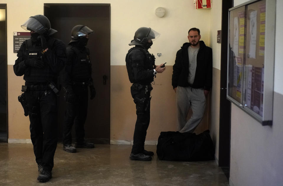 Rap singer Pablo Hasél stands next to police officers before being detained at the University of Lleida, Spain, Tuesday, Feb. 16, 2021. A rapper in Spain and dozens of his supporters have locked themselves inside a university building in the artist's latest attempt to avoid a prison sentence for insulting the monarchy and praising terrorism. (AP Photo/Joan Mateu)