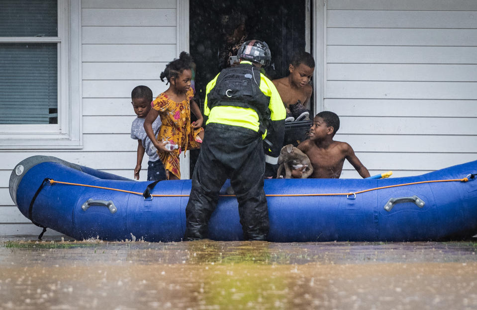 A firefighter with the Winston-Salem Fire Department helps young residents into a raft at Creekwood Apartments as firefighters evacuate the complex due to flooding on Thursday, Nov. 12, 2020 in Winston-Salem, N.C. (Andrew Dye/The Winston-Salem Journal via AP)