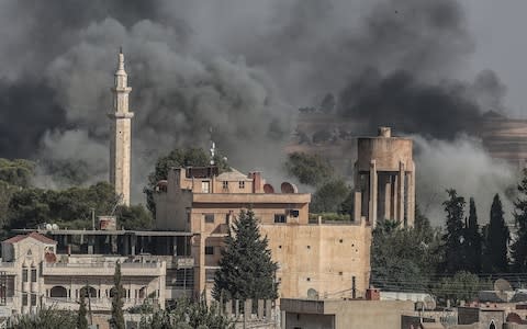 A picture taken from Turkish territory shows smoke rising from targets inside Syria during bombardment by Turkish forces at Ras al-Ayn town - Credit: REX