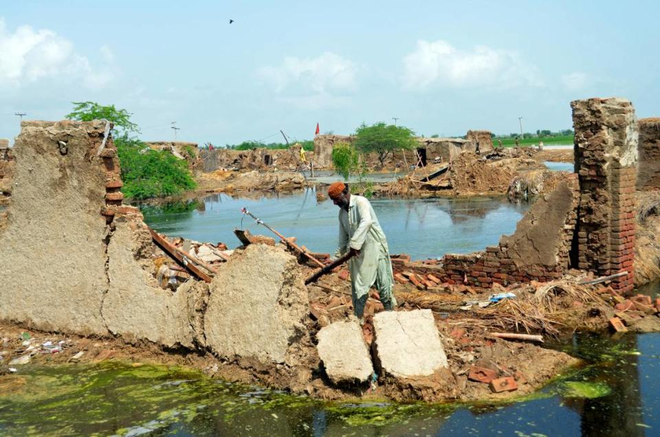 A man looks for salvageable belongings from his flood-hit home surrounded by water, in Jaffarabad, a district of Pakistan’s southwestern Baluchistan province, Sunday, Aug. 28, 2022.