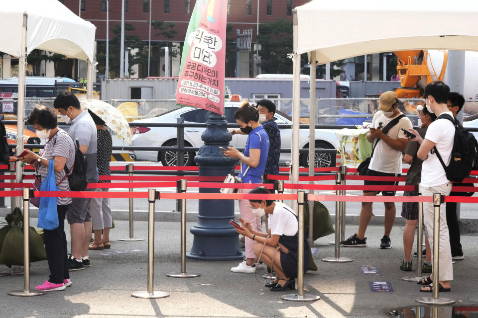 People wait to get coronavirus testing at a makeshift testing site in Seoul, Wednesday, July 28, 2021. South Korea reported a new daily high for coronavirus cases, a day after authorities enforced stringent restrictions in areas outside the capital region. (AP Photo/Ahn Young-joon)