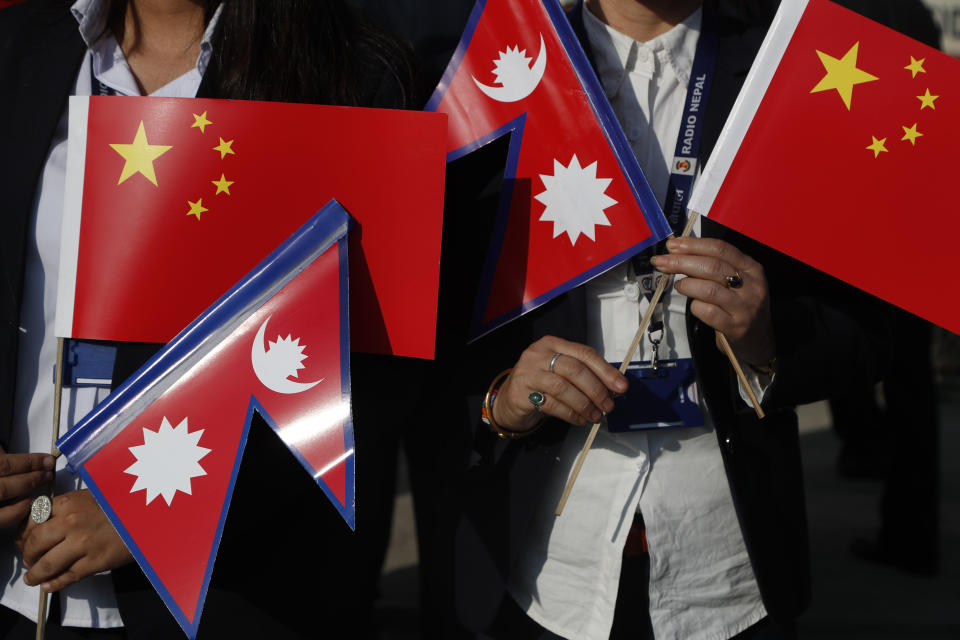 Government officers hold Chinese and Nepalese flag as they wait to welcome Chinese president Xi Jinping in Kathmandu, Nepal, Saturday, Oct 12, 2019. Xi has become the first Chinese president in more than two decades to visit Nepal, where he's expected to sign agreements on major infrastructure projects. (AP Photo/Niranjan Shrestha)