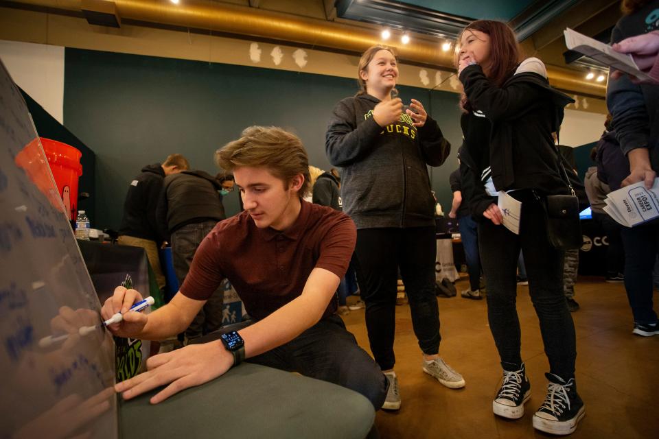 Emilio Ziolkowski, 20, of the Eugene Emeralds, writes down theme night ideas pitched by students during a career exploration fair with Connected Lane County Thursday, Nov. 10, 2022, in Eugene.