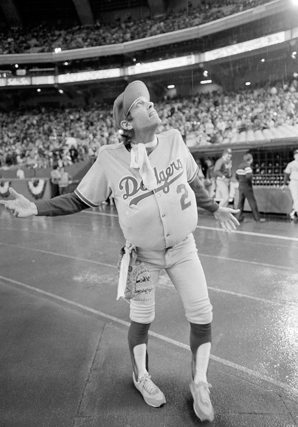 FILE - In this Oct. 18, 1981, file photo, Los Angeles Dodgers outfielder Jay Johnstone, wearing a padded version of manager Tommy Lasorda's uniform, checks the progress of a rain delay before a National League Playoff baseball game with the Expos in Montreal. Johnstone, who won World Series championships as a versatile outfielder with the New York Yankees and Los Angeles Dodgers while being baseball’s merry prankster, died Saturday, Sept. 26, of complications from COVID-19 at a nursing home in Granada Hills, Calif., his daughter Mary Jayne Sarah Johnstone said Monday, Sept. 28, 2020. He was 74. He also from dementia in recent years, his daughter said. (AP Photo/Barrett, File)