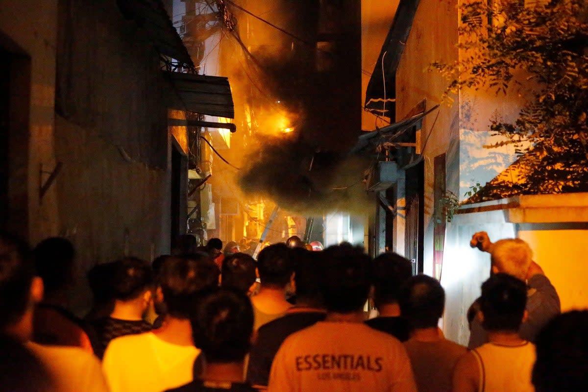 People watch a fire at an apartment building in Hanoi on 13 September (AFP via Getty Images)