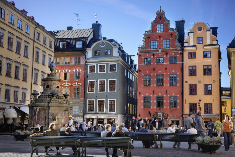 People sitting on benches in old town square in Stockholm.