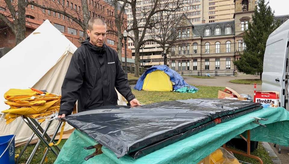 Matthew Grant covers mattress pads with garbage bags to create a water barrier ahead of a major rainstorm.