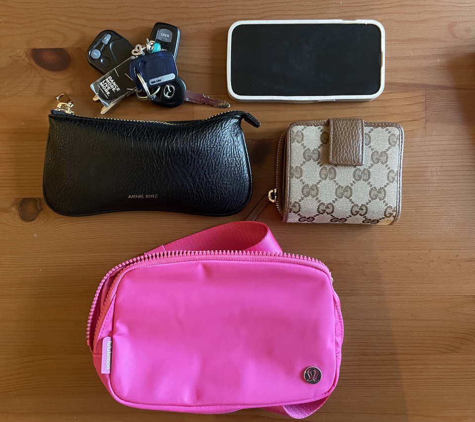 A pink Lululemon Everywhere Belt Bag on table next to phone keys wallet and sunglasses case