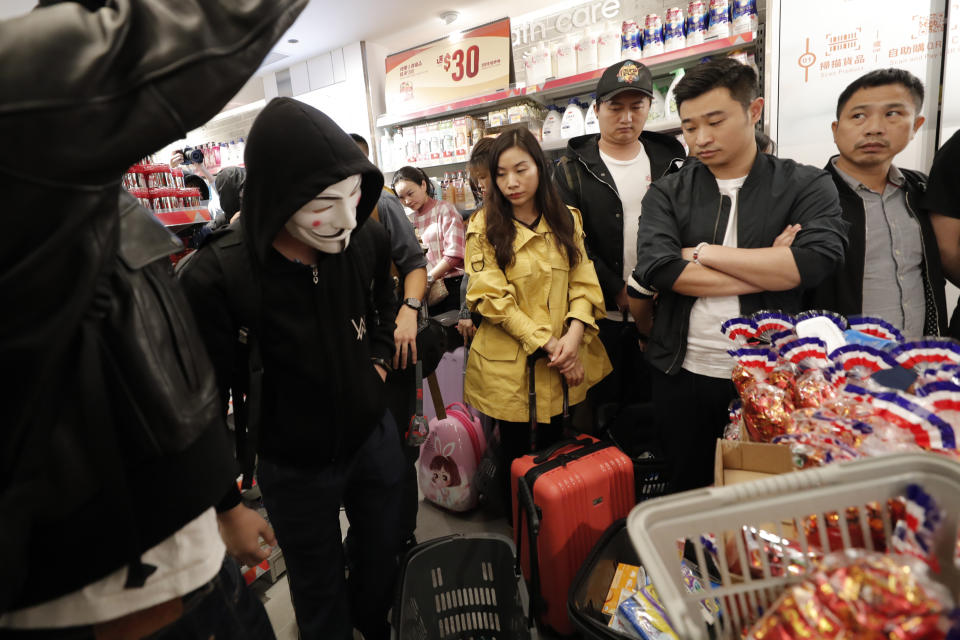 Protesters gather near shoppers in a store at a mall popular with traders from mainland China near the Chinese border in Hong Kong, Saturday, Dec. 28, 2019. Protesters shouting "Liberate Hong Kong!" marched through a shopping mall Saturday to demand that mainland Chinese traders leave the territory in a fresh weekend of anti-government tension. (AP Photo/Lee Jin-man)