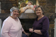 Sharon Bishop-Baldwin, left, and Mary Bishop-Baldwin, right, pose for a photo with a photograph from their wedding day, in their home Tuesday, Nov. 29, 2022, in Broken Arrow, Okla. (AP Photo/Sue Ogrocki)