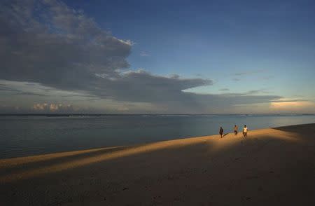 Villagers walk along a beach near the remote Kodi Pangedo village in Indonesia's West Sumba province in this February 15, 2012 file photo. REUTERS/Yusuf Ahmad/