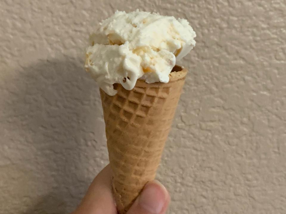 white ice cream in Trader Joe's sugar cone against a beige wall