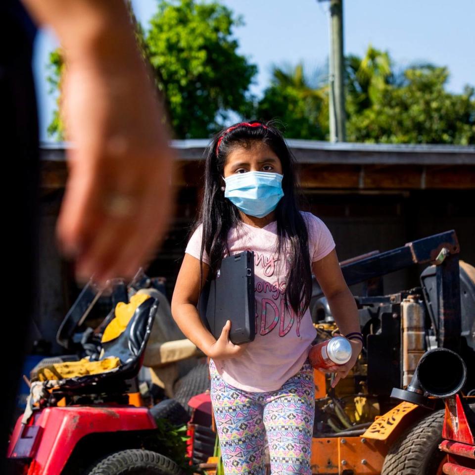 A young migrant girl walks toward a Miami-Dade County Public Schools employee who had taken a lead role on assisting the kids with virtual learning during the coronavirus pandemic in South Florida on Thursday, May 21, 2020.