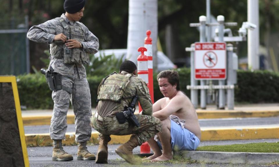 Security forces attend to an unidentified man outside Joint Base Pearl Harbor-Hickam on Wednesday after the shooting.