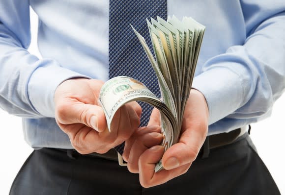 A businessman counting a stack of crisp hundred dollar bills in his hands.