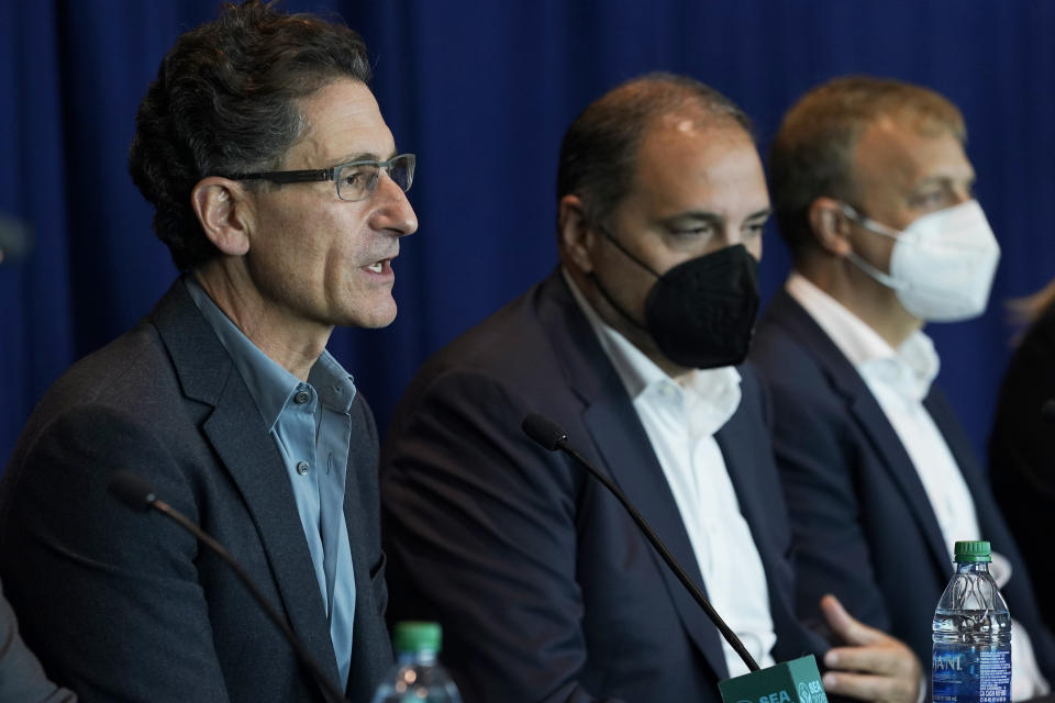 Adrian Hanauer, left, owner of the MLS soccer Seattle Sounders, speaks Monday, Nov. 1, 2021, in Seattle as Victor Montagliani, center, CONCACAF president and FIFA vice president, and Colin Smith, right, FIFA chief tournaments and events chairman, look on during a news conference at Lumen Field. Hanauer was discussing the official visit of a FIFA delegation to Seattle, as organizers try to be selected as a host city for the FIFA World Cup in 2026. (AP Photo/Ted S. Warren)