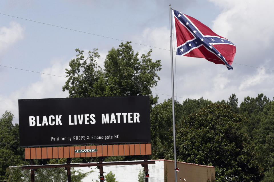 A Black Lives Matter billboard is seen next to a Confederate flag in Pittsboro, N.C., Thursday, July 16, 2020. A group in North Carolina erected the billboard to counter the flag that stands along the road. (AP Photo/Gerry Broome)