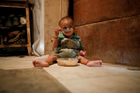 Yeibe Medina, the one-year old son of Maria Guitia sits on the floor feeding himself at their home near San Francisco de Yare, Venezuela, February 18, 2019. REUTERS/Carlos Garcia Rawlins