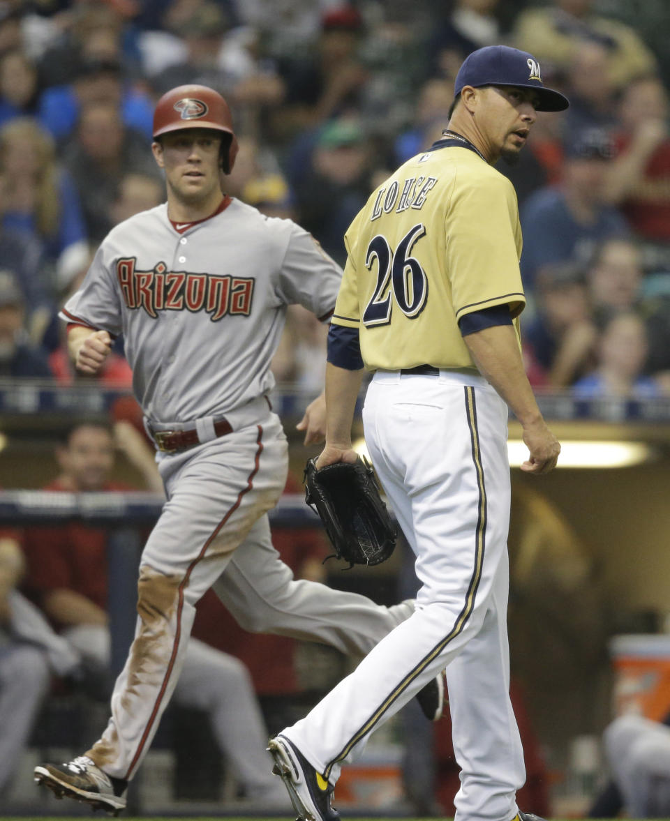 Arizona Diamondbacks' Aaron Hill, left, scores as Milwaukee Brewers starting pitcher Kyle Lohse watches his own throwing error on a bunt by Diamondbacks' Chris Owings during the second inning of a baseball game Saturday, May 30, 2015, in Milwaukee. (AP Photo/Jeffrey Phelps)