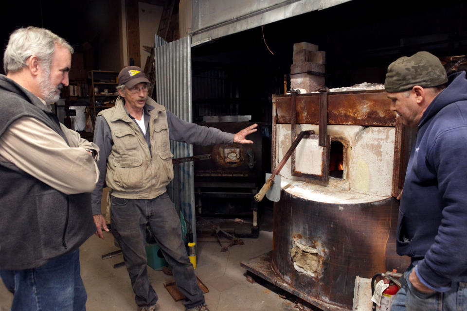 This Dec. 3, 2012, photo provided by Craft Emergency Relief Fund (CERF+) Craig Nutt, left, of CERF+ is shown a damaged furnace at Pier Glass in the Red Hook neighborhood of Brooklyn, New York by artists Kevin Kutch and Kevin Scanlan, right. Scanlan is describing their attempt to dry out the furnace, which was inundated with salt water from Superstorm Sandy. (AP Photo/CERF+, George Hirose)