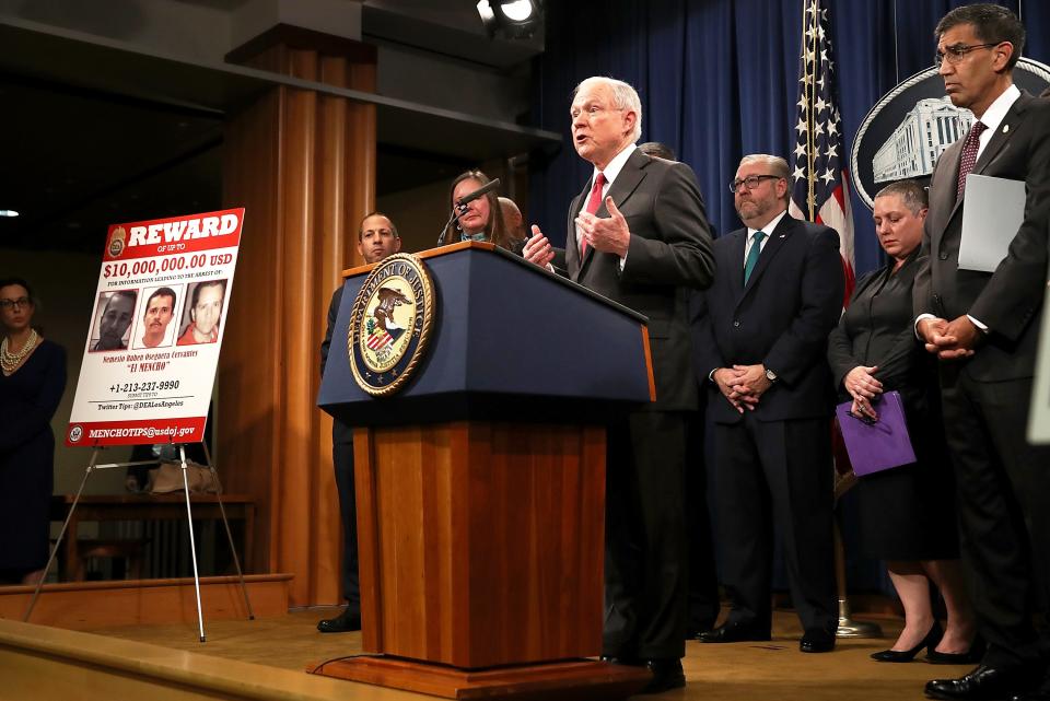 El Mencho and CJNG were publicly named as top U.S. targets during a news conference in Washington, D.C., in October 2018 by then-Attorney General Jeff Sessions and DEA Acting Administrator Uttam Dhillon (far right). They announced indictments and a $10 million reward for information.