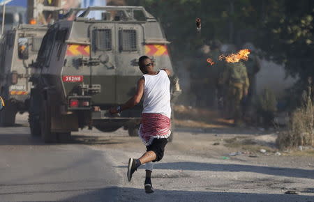 A Palestinian protester throws a molotov cocktail towards Israeli soldiers during clashes following the funeral of Palestinian youth Laith al-Khaldi, in Jalazoun refugee camp near the West Bank city of Ramallah August 1, 2015. REUTERS/Mohamad Torokman