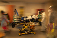 FILE- In this April 14, 2021, file photo, medical personnel wearing protective equipment wheel a bed with a coronavirus patient in critical condition as they prepare to transfer the patient by ambulance to a hospital in Aachen, Germany, at the MontLegia CHC hospital in Liege, Belgium. (AP Photo/Francisco Seco, File)