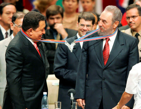 Venezuela's President Hugo Chavez (L) and his Cuban counterpart Fidel Castro joke after joining their medallions, given by medical graduates, at Havana's Karl Marx theatre, in this August 20, 2005 file photo. REUTERS/Claudia Daut/File Photo